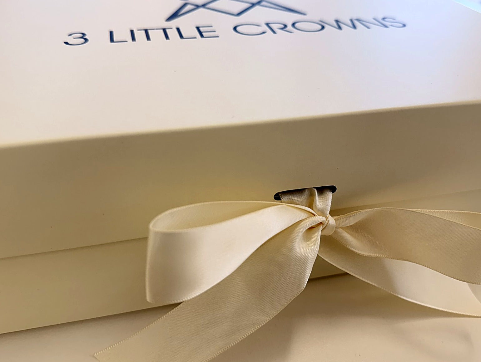 Close-up of the 3 Little Crowns gift box ribbon bow and logo